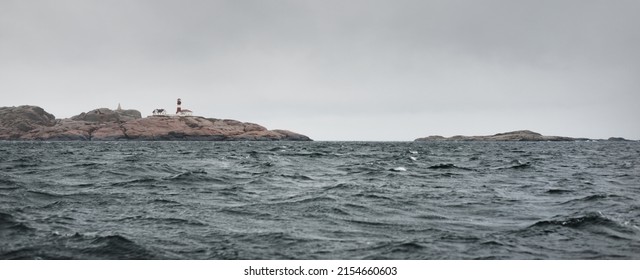 Lonely Lighthouse In Fjords. Glowing Clouds Above The Sea. Waves, Water Splashes. Dramatic Sky After The Storm. A View From The Yacht. Sailing In A Rough Weather. Nature, Travel Destinations, Cruise