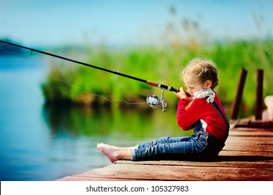 Lonely Little Child Fishing From Wooden Dock On Lake