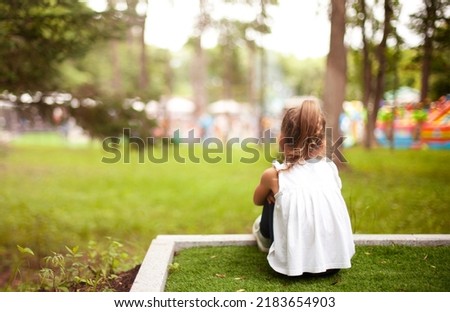 a lonely little girl from afar is looking at a crowded event