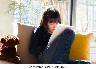 isolement solitaire enfant lisant, dessinant ou écrivant sur papier avec l'ours en peluche apprenant à l'école à domicile pendant la crise du 19 au soleil dans un appartement ensoleillé