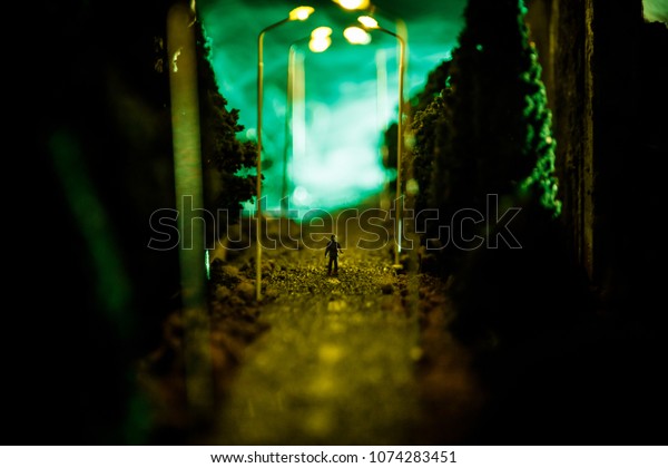 Lonely man. City at night in dense fog. Thick smog\
on a dark street. Silhouettes of man on road. Table decoration.\
Selective focus