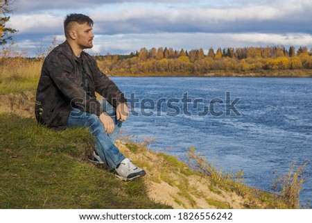 Similar – Man sitting by the river in fall