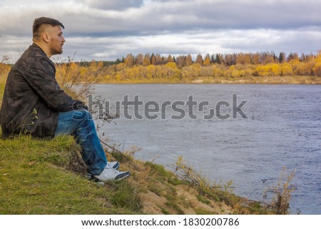 Similar – Man sitting by the river in fall