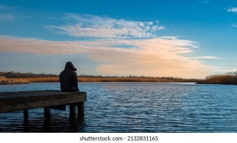 A lonely man  on a fishing pier watching sunset in the winter. 