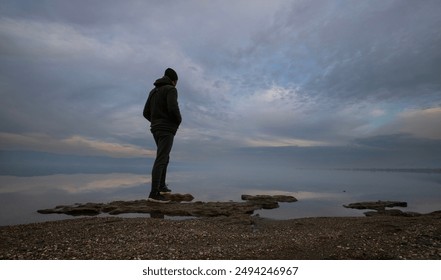 lonely man with overcast sky at water's edge - Powered by Shutterstock