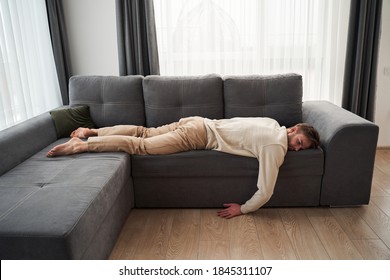Lonely man. Sad thoughtful handsome man lying in the empty room on the sofa face down on the stomach and suffering. Stock photo
