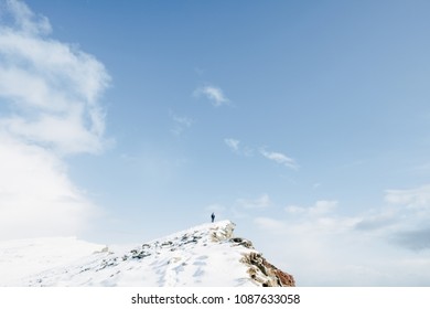 Lonely Man Sillhouette On A High Snow-covered Mountain Peak And Blue Sky