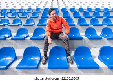 A lonely man is sitting and watching a sports competition alone on a large empty grandstand. Competition and other mass events during the lockdown. - Shutterstock ID 2213818305