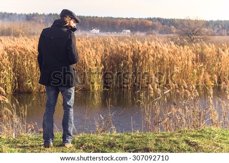 Similar – Man sitting by the river in fall