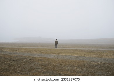    A lonely man stands in a field covered with white fog                             - Powered by Shutterstock