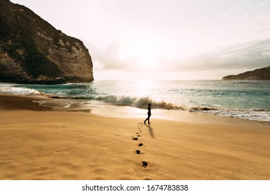 A lonely man stands on the beach. A man meets the sunset on the beach in Indonesia. Steps on the sand, sunset, silhouette of person walking on sea beach. Vacation at sea - Powered by Shutterstock