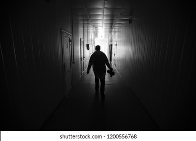 a lonely man walks down a dark corridor to a lighted exit, an eerie and mystical gloomy place, a hospital corridor, a light at end of tunnel, a vision before death, to escape from fear of darkness - Powered by Shutterstock