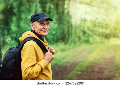 Lonely mature male tourist with backpack walking at forest path way. Hiking and tourism concept. Arthritis prophylactic and healthy lifestyle. - Shutterstock ID 2247522209