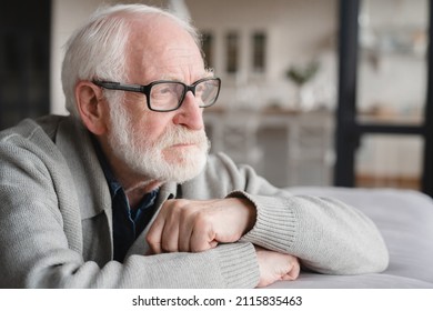 Lonely missing old people, senior man elderly grandfather sitting on the sofa, feeling pain, sick, ill, nostalgy, fraud, bankruptcy at home alone, needing help.
