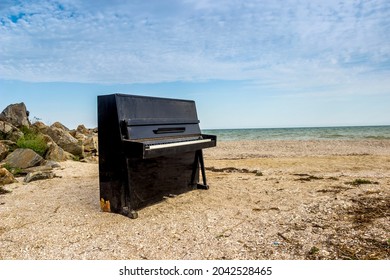 a lonely old black piano on the sea beach