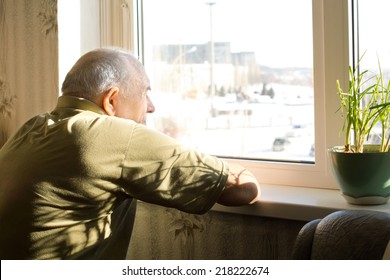 Lonely Old Man In An Old-age Home Staring Out Of A Window As He Longs For His Freedom And Friends