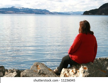 Lonely overweight woman looking at the ocean