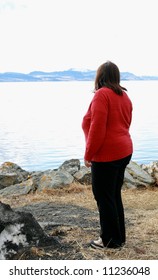 Lonely overweight woman looking at the ocean
