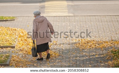 A lonely pensioner walks through the city and carries a bag in her hands.