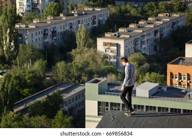 A lonely roofer looking down from the edge of the roof. Courage and adrenaline.