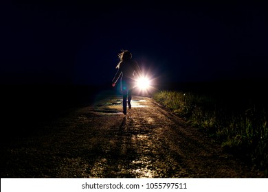 Lonely Running Female Silhouette On The Night Country Road Running Away From Pursuers By Car In The Headlights