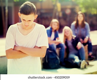 Lonely Sad Male Teenager Standing Away From Friends Feeling Depressed