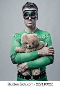 Lonely Sad Superhero Holding Tight A Cute Teddy Bear.