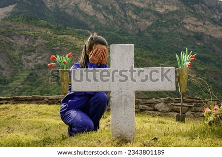 Lonely Sad young Woman in Mourning with a Gravestone in a Cemetery. Day of the dead.