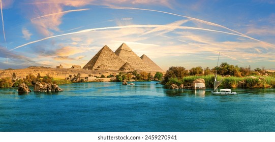 Lonely Saleboat in the Nile river and ancient rocks in the Aswan desert by the pyramids, Egypt - Powered by Shutterstock