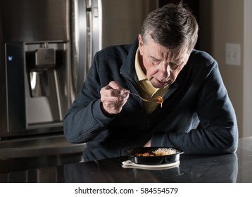 Lonely Senior Man Eating Ready Meal At Table