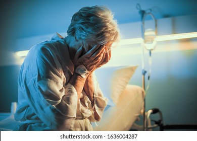 Lonely senior patient sitting on the hospital bed and crying with head in hands - Powered by Shutterstock