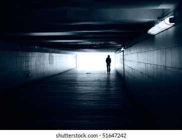 Lonely silhouette in dark subway tunnel goes towards the light - Powered by Shutterstock