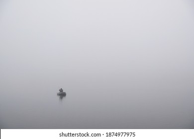 Lonely small boat with fisherman on misty lake in whiteness. - Powered by Shutterstock