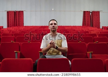 A lonely spectator in an empty theater attentively watches the play