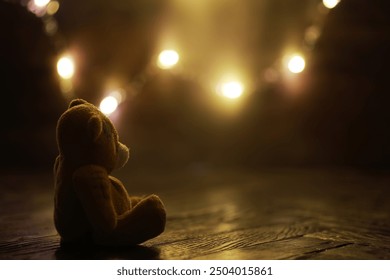 Lonely Teddy Bear on Wooden Floor with Warm Fairy Lights in Background - Powered by Shutterstock