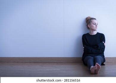Lonely thoughtful girl sitting on the floor