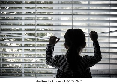 Lonely Toddler Child Standing In Front Of A Window Looking Outside