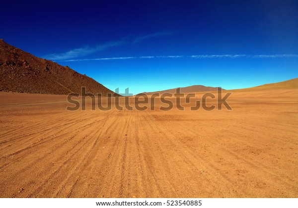 lonely track with many lanes over a lava\
field in the high mountains of the andean in chile close to an\
active vulcan in the region of san pedro de\
atacama