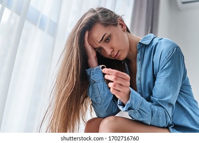 Lonely unhappy divorced woman with sad eyes holds gold ring in hands and sits alone at home during difficulty problems in life and crisis in relationship. Break up marriage and end family