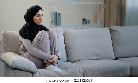 Lonely upset sad muslim young woman sit on sofa health problem interrupted pregnancy divorce islamic unwell girl in hijab feeling anxiety depressed frustrated unhappy female difficult period of life - Powered by Shutterstock