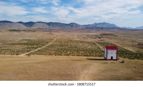 A lonely using solar panels self-contained house stands in the middle of the steppe with a view of beautiful vineyards and mountains on the horizon.