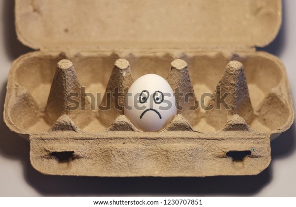 lonely white egg with
sad face in a box
