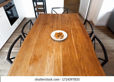 Lonely White Plate With Cookies On An Empty Dinner Table. Big Wooden Table With Chairs And Cookies In The Kitchen. Solid Wooden Surface Of Table At Natural Daylight.