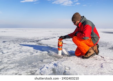 Lonely winter hiker on huge ice field cooking on portable gas cooker