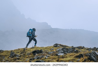 Mujer solitaria con mochila y bastones de trekking yendo por ruta de montaña durante el Parque Nacional Makalu Barun cerca del asentamiento Tuli Kharka en Nepal. Senderismo de montaña y gente activa concepto imagen.