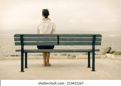 Lonely woman sitting on a bench by the sea