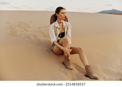 Lonely woman sitting on sand dune in the vast desert landscape under the scorching sun - Powered by Shutterstock