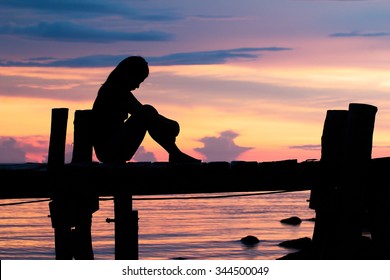 Lonely woman sitting on a wooden bridge sunset.are Lonely. style abstract shadows.silhouette - Powered by Shutterstock