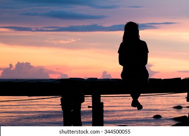 Lonely woman sitting on a wooden bridge sunset.are Lonely. style abstract shadows.silhouette - Powered by Shutterstock