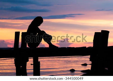 Lonely woman sitting on a wooden bridge sunset.are Lonely. style abstract shadows.silhouette